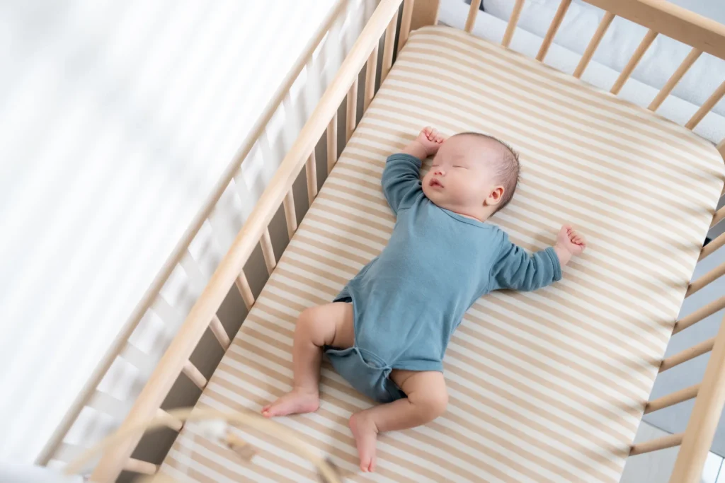 Baby resting peacefully in a crib, illustrating physician-led in-home baby sleep training and healthy sleep routines.