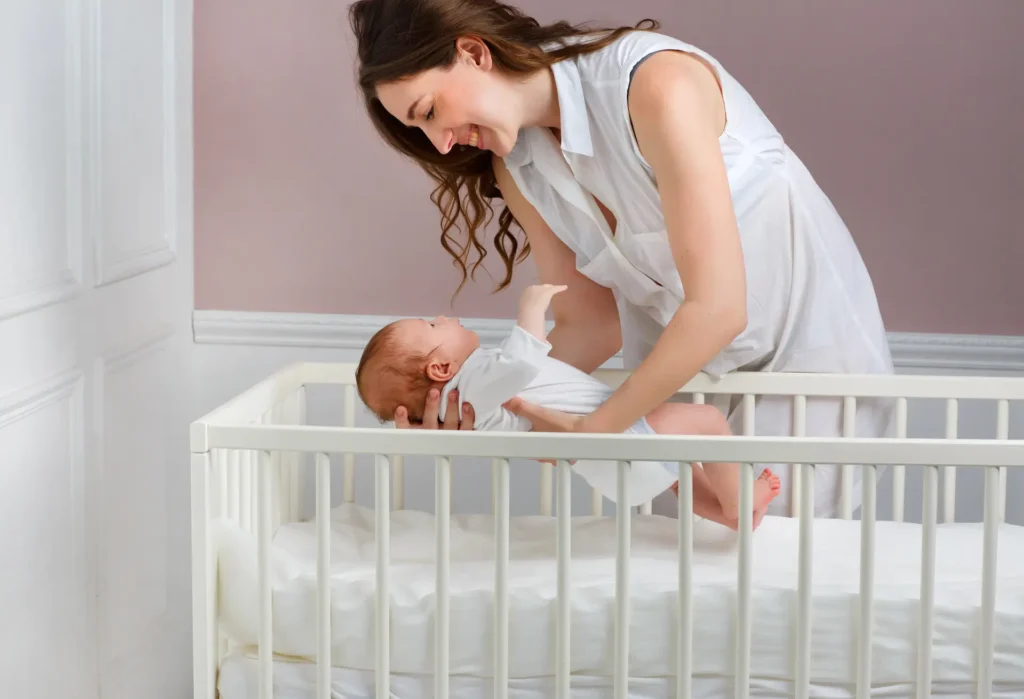 Calm mother placing her baby in a crib with guidance from physician-led postpartum support, newborn care, and healthy sleep foundations.
